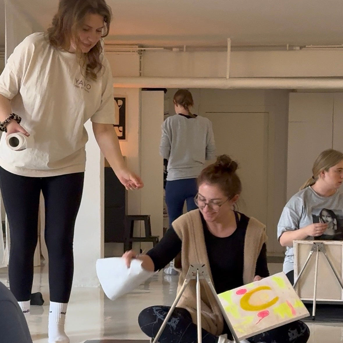 Yoga & Paint Event Künstlerin hilft Teilnehmerin